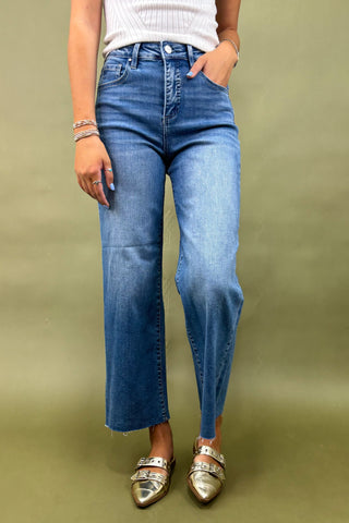 Person wearing blue jeans and metallic shoes on a green background
