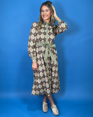 Black floral medallion print midi dress with green contrast trim, long sleeves, button front, and matching tie waist.