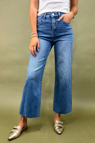Person wearing blue jeans and silver shoes on a green background