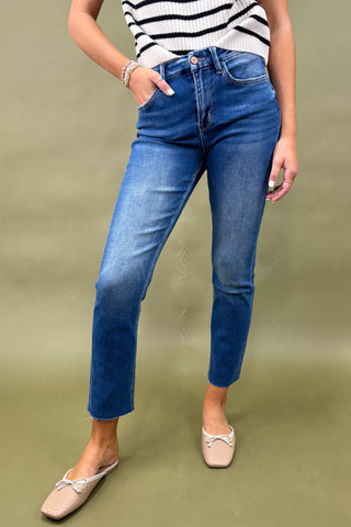 Person wearing blue jeans and a striped shirt on a green background