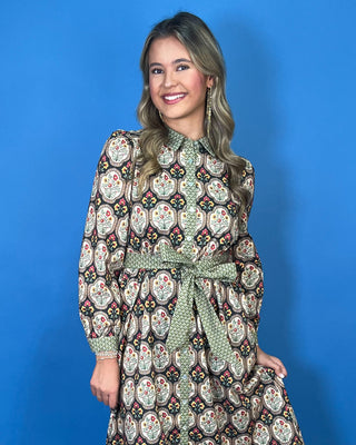 Black floral medallion print midi dress with green contrast trim, long sleeves, button front, and matching tie waist.