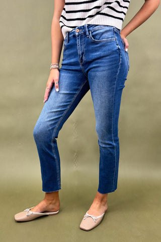 Person wearing blue jeans and a striped top on a green background