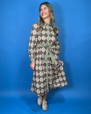 Black floral medallion print midi dress with green contrast trim, long sleeves, button front, and matching tie waist.