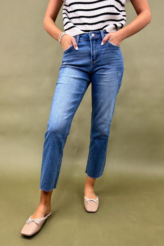 Person wearing blue jeans and a striped shirt on a green background