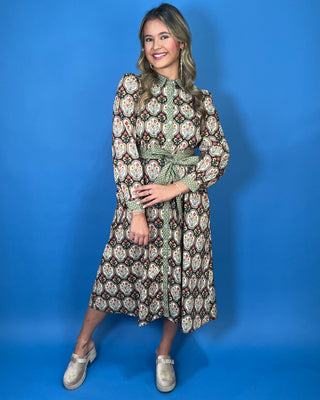 Black floral medallion print midi dress with green contrast trim, long sleeves, button front, and matching tie waist.