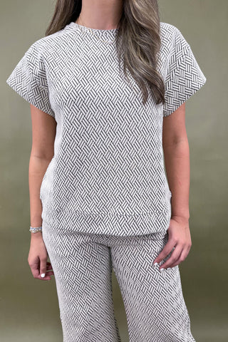 Person wearing a patterned outfit against a plain background
