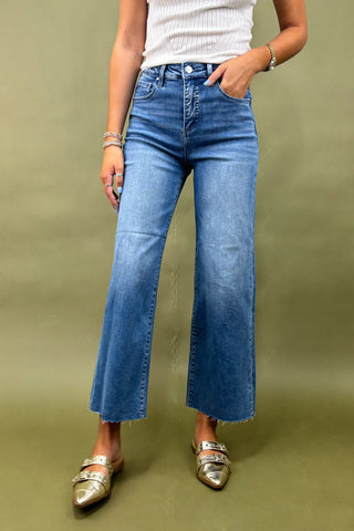 Person wearing blue jeans and gold shoes on a green background