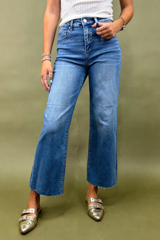Person wearing blue flared jeans on a green background