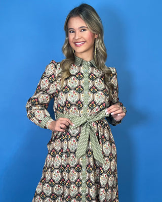Black floral medallion print midi dress with green contrast trim, long sleeves, button front, and matching tie waist.