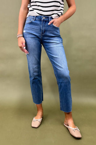Person wearing blue jeans and a striped top on a green background