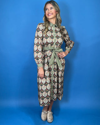 Black floral medallion print midi dress with green contrast trim, long sleeves, button front, and matching tie waist.