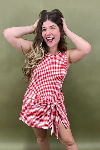 Woman wearing a red and white checkered dress against a green background