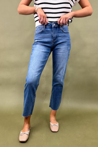 Person wearing blue jeans and a striped shirt on a green background