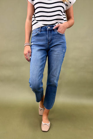 Person wearing blue jeans and a striped shirt on a green background