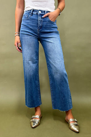 Person wearing blue jeans and silver shoes on a green background