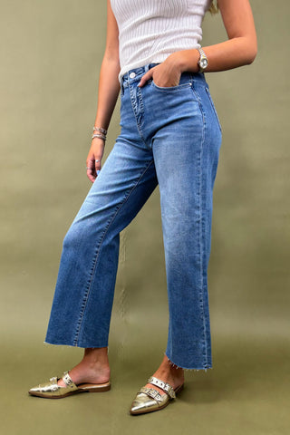 Person wearing blue jeans and a white top on a green background