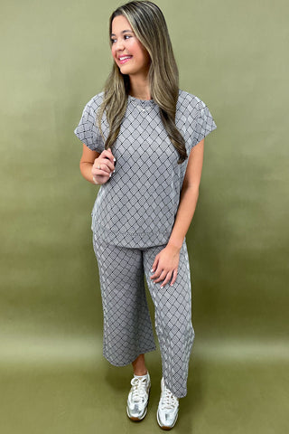 Woman wearing a gray patterned outfit on a green background