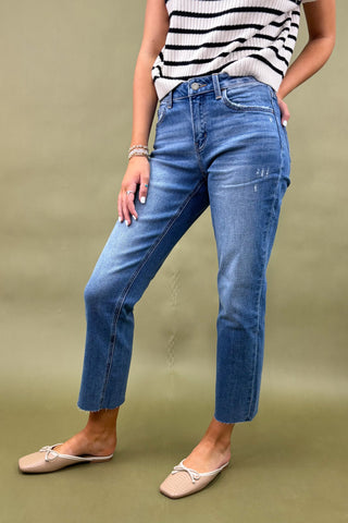 Person wearing blue jeans and a striped top on a green background