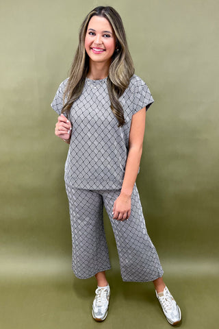 Woman wearing a gray patterned outfit against a green background