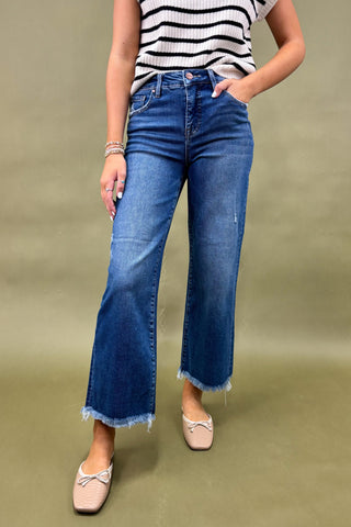 Person wearing blue jeans and a striped shirt on a green background