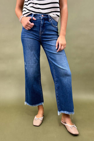 Person wearing blue jeans and a striped top on a green background