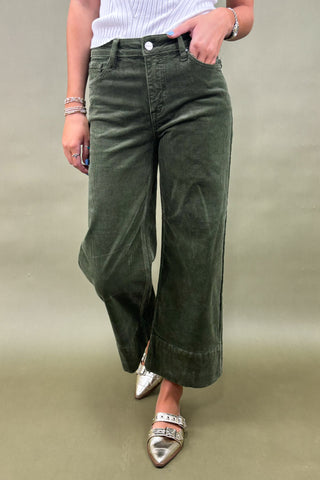 Person wearing green wide-leg jeans on a plain background