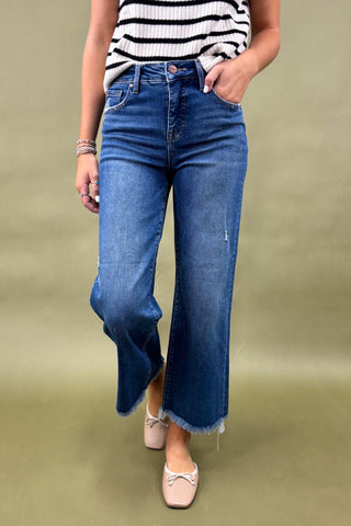 Person wearing blue flared jeans and a striped shirt on a green background