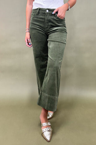 Person wearing green corduroy pants with a plain background