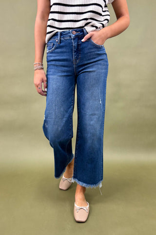 Person wearing blue jeans and a striped shirt on a green background