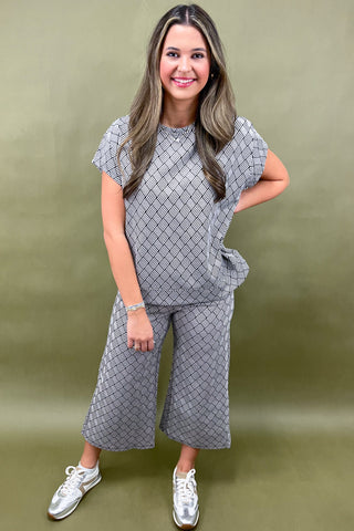 Woman wearing a gray patterned outfit against a green background