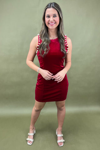 Woman wearing a red dress with white polka dot straps against a green background