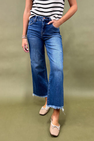 Person wearing blue jeans and a striped shirt on a green background