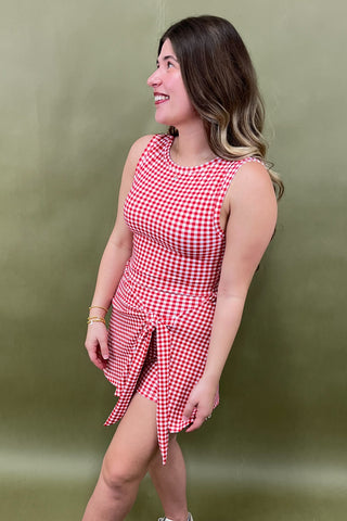 Woman wearing a red and white checkered dress against a green background