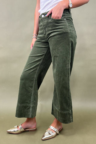 Person wearing green corduroy pants on a plain background