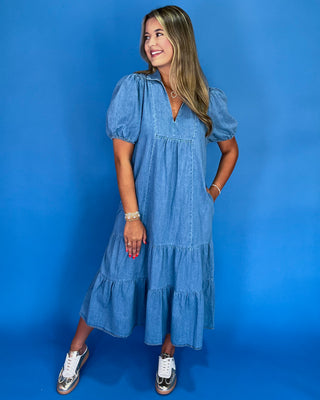 Woman wearing a blue denim dress against a blue background