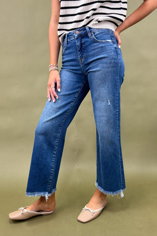 Person wearing blue jeans and a striped shirt on a green background