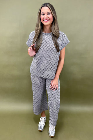 Woman wearing a gray patterned outfit against a green background