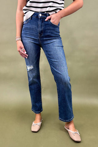 Person wearing blue jeans and a striped top on a green background