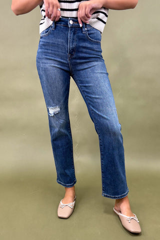 Person wearing blue jeans and a striped shirt on a green background