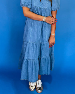 Person wearing a blue tiered dress against a blue background