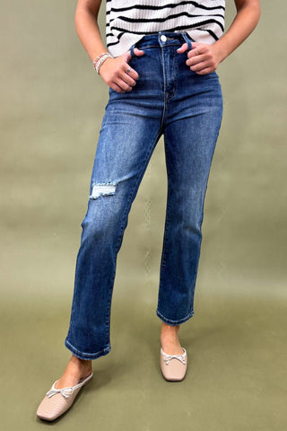 Person wearing blue jeans and a striped shirt on a green background