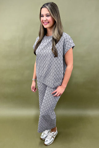 Woman wearing a gray patterned outfit against a green background