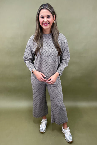 Woman wearing a gray patterned outfit against a green background