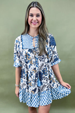 Woman wearing a blue and white floral dress against a green background