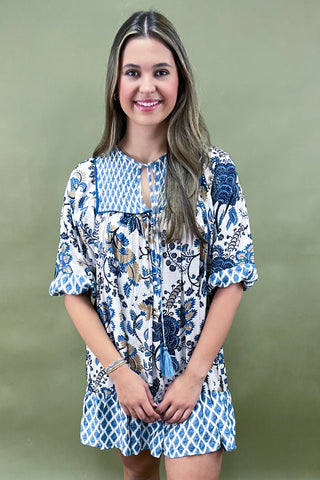 Woman wearing a blue and white floral dress against a green background