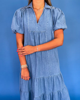 Woman wearing a blue denim dress against a blue background