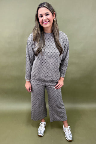 Woman wearing a gray patterned outfit on a green background