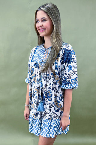 Woman wearing a blue and white floral dress against a green background