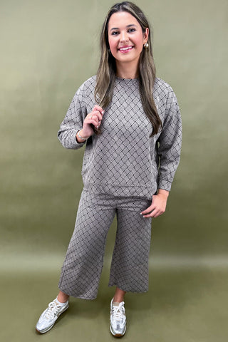 Woman wearing a gray patterned outfit against a green background
