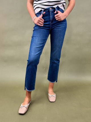 Person wearing blue jeans and a striped shirt on a green background